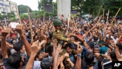 Los manifestantes llevan a un miembro del Ejército sobre sus hombros mientras celebran la renuncia de la Primera Ministra Sheikh Hasina, en Dhaka, Bangladesh, el lunes 5 de agosto de 2024.