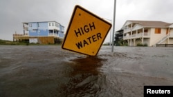 Floodwaters lap at a high water warning sign that was partially pushed over by Hurricane Florence on Oak Island, N.C., Sept. 15, 2018.