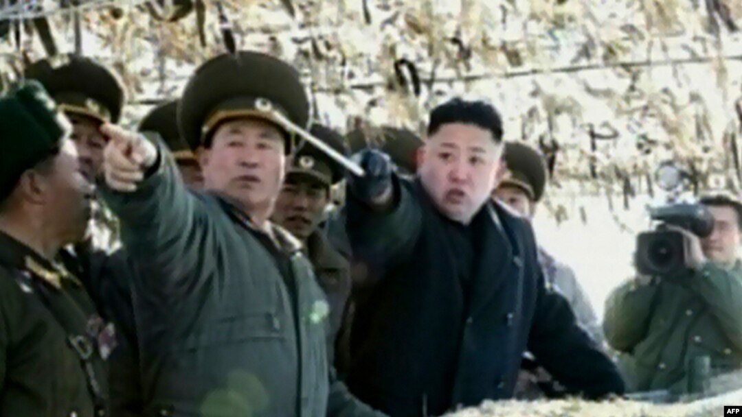Pemimpin Korut, Kim Jong-un (tengah) tengah menunjuk ke arah sebuah pulau di Korsel saat meninjau latiham artileri di pulau Wolnae dekat perairan sengketa (12/3).