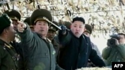 Pemimpin Korut, Kim Jong-un (tengah) tengah menunjuk ke arah sebuah pulau di Korsel saat meninjau latiham artileri di pulau Wolnae dekat perairan sengketa (12/3).