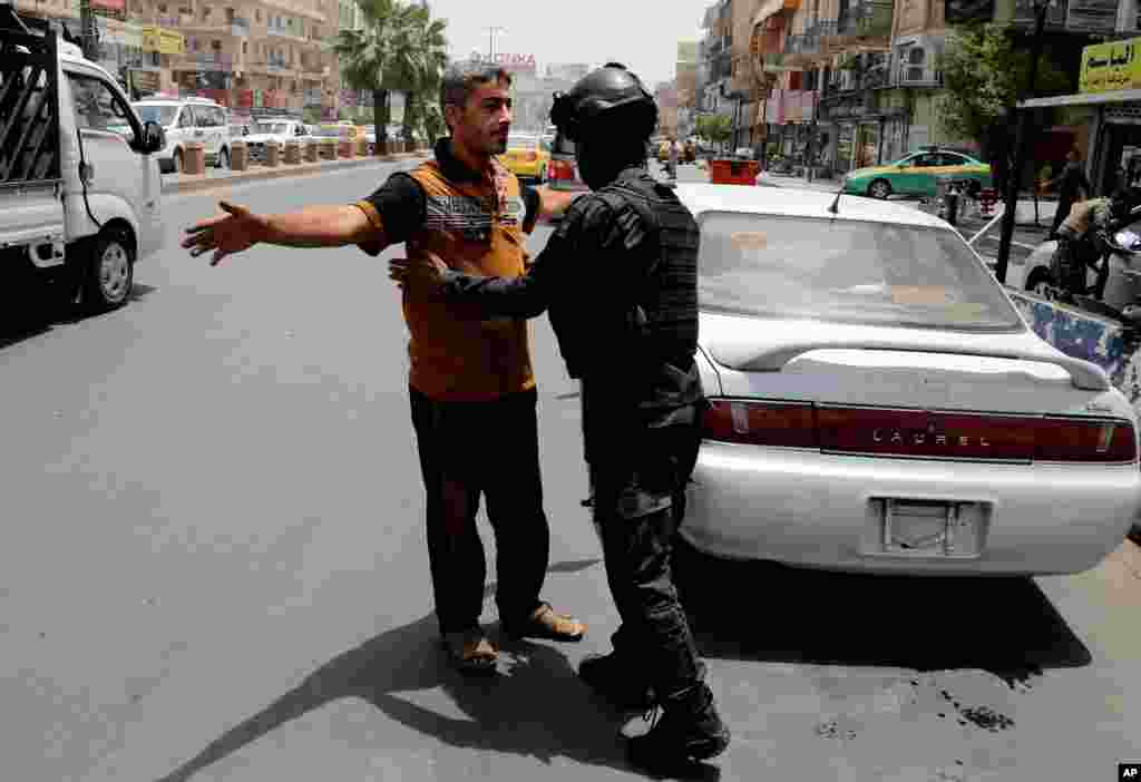 Dengan meningkatnya langkah keamanan, polisi federal Irak melakukan pemeriksaan di sebuah pos di Baghdad (11/6). (AP/Karim Kadim)