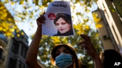资料照片：一位女子举着有关阿米尼照片的报纸复印件参加在伊朗驻伊斯坦布尔总领事馆外的抗议活动。(2022年9月21日)