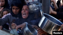 Palestinians gather to receive food cooked by a charity kitchen, amid a hunger crisis as the Israel-Gaza conflict continues in Khan Younis in the southern Gaza Strip, Dec. 4, 2024.