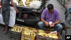 En esta foto del 8 de mayo de 2019, un vendedor de plátanos cuenta sus bolívares (la moneda local) en Petare. Caracas, Venezuela.