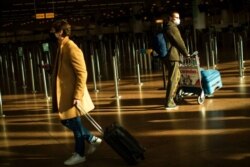 FILE - Travelers, wearing face masks to prevent the spread of the coronavirus, walk along the departure hall of the Zaventem international airport in Brussels, Jan. 22, 2021.