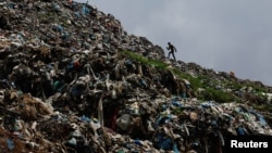 A man walks on waste at a dumping site as locals from a village near the site protest against garbage being dumped in their area by blocking garbage trucks from reaching the dumping site at the outside of Kathmandu, Nepal on June 8, 2022. (REUTERS/Navesh Chitrakar)