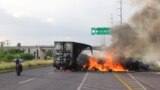 (FILE) A man rides his motorcycle past a vehicle set on fire by cartel gunmen during clashes with security forces, in Culiacan, Mexico, Aug. 29, 2024.