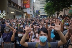 FILE - Protesters against the new national security law gesture with five fingers, signifying the "Five demands - not one less" on the anniversary of Hong Kong's handover to China from Britain in Hong Kong, July. 1, 2020.