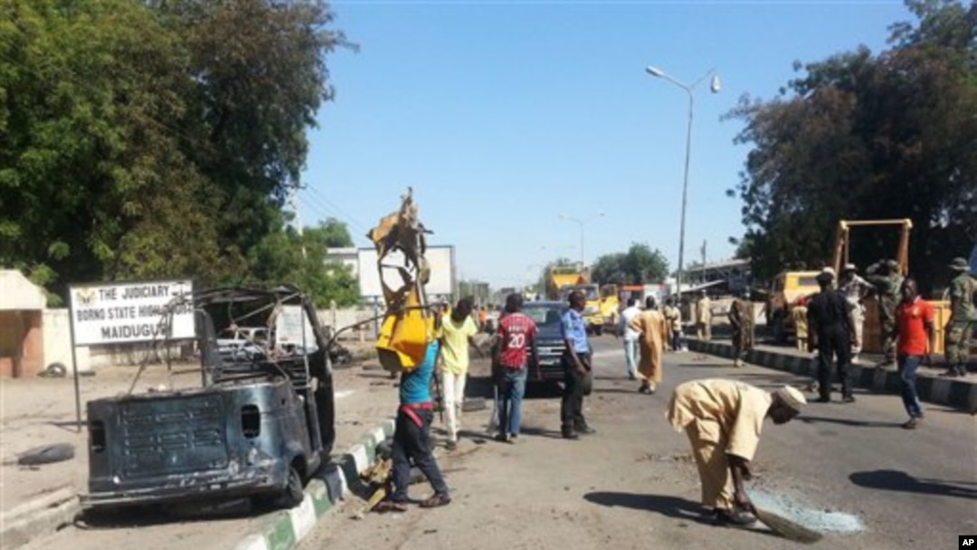 Petugas penyelamat membersihkan jalan menyusul bom mobil bunuh diri di sebuah pos militer di Maiduguri, Nigeria (14/1). (AP/Jossy Ola)