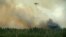 A helicopter dumps its load of water on the wildfire just outside the evacuated village of Gammelby near Sala, Central Sweden, Monday, Aug. 4, 2014. 