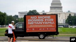 Un transeúnte se detiene para tomar una fotografía de un cartel móvil de "No más bombas para Netanyahu" cerca del edificio del Capitolio el 23 de julio de 2024 en Washington.