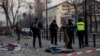 Police officers stand near the body of a civilian following a missile attack in Kyiv on Feb. 12, 2025, amid the Russian invasion of Ukraine. 