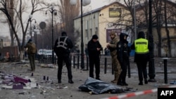 Police officers stand near the body of a civilian following a missile attack in Kyiv on Feb. 12, 2025, amid the Russian invasion of Ukraine. 