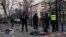 Police officers stand near the body of a civilian following a missile attack in Kyiv on Feb. 12, 2025, amid the Russian invasion of Ukraine. 