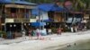 FILE - Tourists walk along a beach on Koh Rong island in Sihanoukville province on October 31, 2019. (Photo by TANG CHHIN Sothy / AFP)