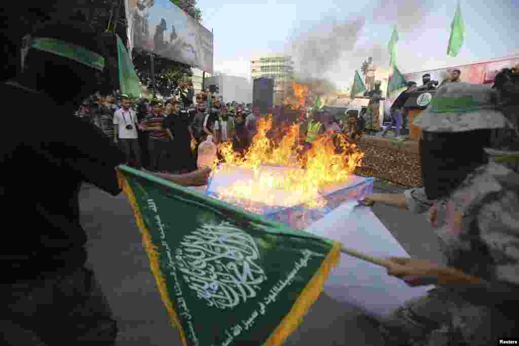 Masked Hamas members burn a cut-out of a Star of David during a rally in support of the armed Palestinian factions, in Rafah in the southern Gaza Strip, Aug. 17, 2014.