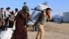 Syrian displaced families, who fled violence after the Turkish offensive in Syria, receive aid in Bardarash refugee camp on the outskirts of Dohuk, Iraq Oct. 22, 2019.