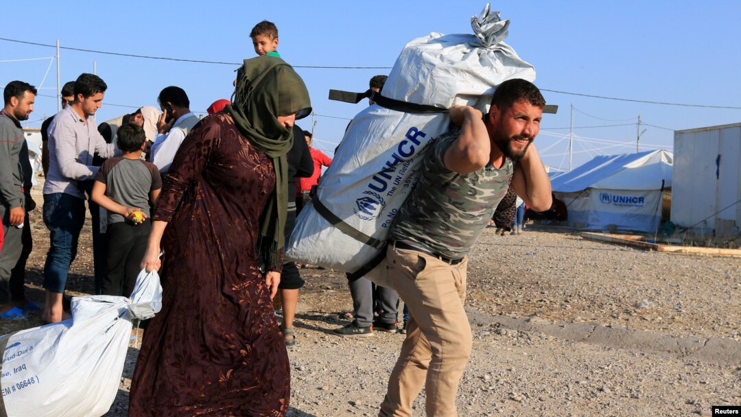 Syrian displaced families, who fled violence after the Turkish offensive in Syria, receive aid in Bardarash refugee camp on the outskirts of Dohuk, Iraq Oct. 22, 2019.