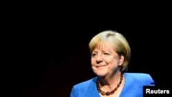 Former German Chancellor Angela Merkel talks with author Alexander Osang, in Berlin