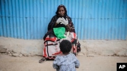 FILE—Safia Ibrahim prepares to demonstrate the tools and techniques she uses to perform FGM, which she has been practicing for 35 years, as her neighbor's daughter looks on in the courtyard of her home in Hargeisa, Somaliland, February 7, 2022.