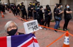 Una mujer sostiene un cartel y una bandera del Reino Unido, mientras los partidarios hacen cola frente a un tribunal para tratar de ingresar a una audiencia en Hong Kong el lunes 1 de marzo de 2021.