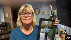 Stacey Collins Gardiner holds a picture of her son, Travis Timmerman, in her home in Urbana, Mo., Dec. 12, 2024.