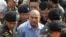 Thai policemen escort the fortune teller, Suriyan Sutjritpolwongse, center, better known by the nickname "Mor Yong," as he arrives at military court in Bangkok, Thailand, Oct. 21, 2015. 