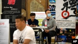 FILE - Recruiters sit at a booth during a job fair held in a shopping center in Beijing, on June 9, 2023.