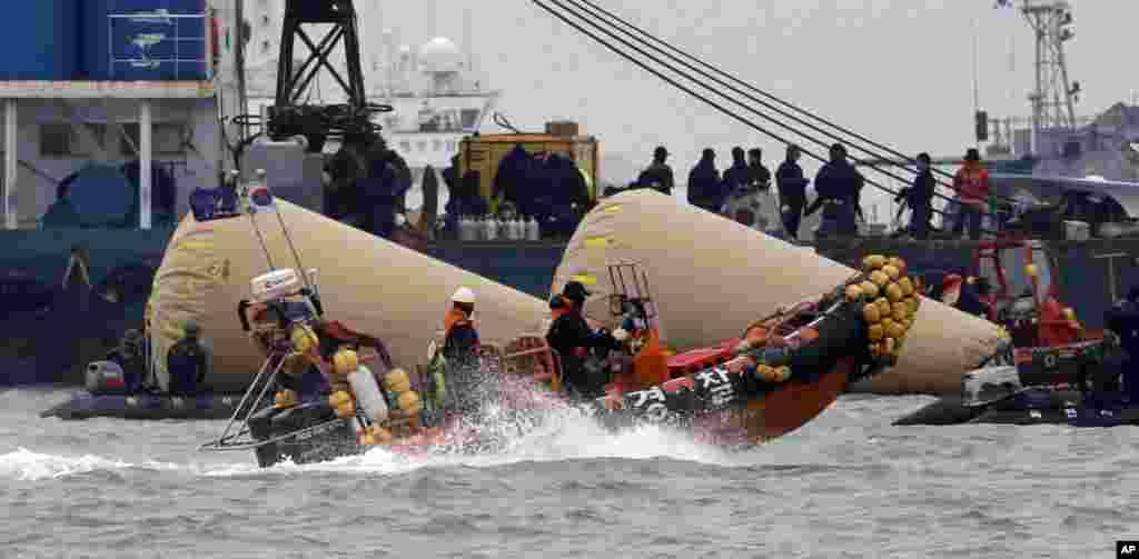 Searchers and divers look for people believed to have been trapped in the sunken ferry boat Sewol near the buoys marking the vessel in the water off the southern coast near Jindo, south of Seoul, South Korea.