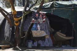 A campaign poster of U.S. President Joe Biden hangs on a tree at a migrant encampment in Matamoros, Mexico, Feb. 19, 2021.
