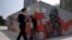 A man lowers his mask to smoke as he walks past graffiti artwork in Beijing, July 13, 2020. 