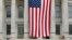Two people sit on the steps of Brooklyn's Borough Hall where a huge American flag is displayed, July 3, 2014.