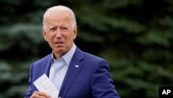 El exvicepresidente del candidato presidencial demócrata Joe Biden coloca una tarjeta en el bolsillo de su chaqueta mientras habla en un evento de campaña en Michigan.