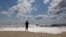 A beachgoer stands at the edge of the water, Sunday, Sept. 4, 2016, in Bridgehampton, N.Y., on the southeastern shore of Long Island, where the effects of storm system Hermine could be seen in the rough surf and a ban on swimming. 