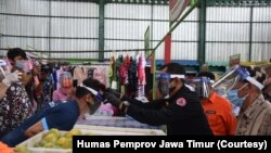 Sekdaprov Jawa Timur memakaikan face shield kepada para pedagang dan pengunjung Pasar Oro-oro Dowo, Malang. (Foto: Humas Pemprov Jawa Timur)