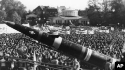 FILE - A life-size mockup of a Pershing II missile dwarfs the demonstrators protesting the scheduled deployment of missiles, in downtown Bonn, Germany, Oct. 22, 1983. 