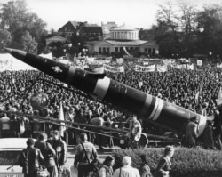 FILE - A life-size mockup of a Pershing II missile dwarfs the demonstrators protesting the scheduled deployment of missiles, in downtown Bonn, Germany, Oct. 22, 1983.