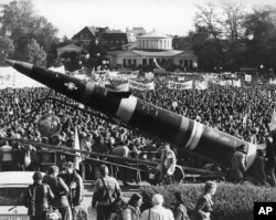 FILE - A life-size mockup of a Pershing II missile dwarfs the demonstrators protesting the scheduled deployment of missiles, in downtown Bonn, Germany, Oct. 22, 1983.
