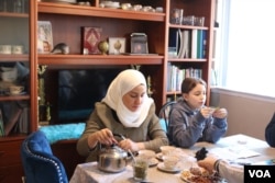 Syrian refugee Nawar Almadani sits with daughter Esraa, 10, as she plays a game. The family resettled in Chicago after living in Turkey for two years after the war in Syria broke out. (K. Khan/VOA)