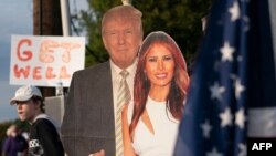 Simpatizantes portan carteles con la efigie del presidente Donald Trump y la primera dama Melania Trump el 4 de octubre de 2020 en el exterior del Centro Médico Walter Reed, en Maryland, donde el presidente es tratado por coronavirus.