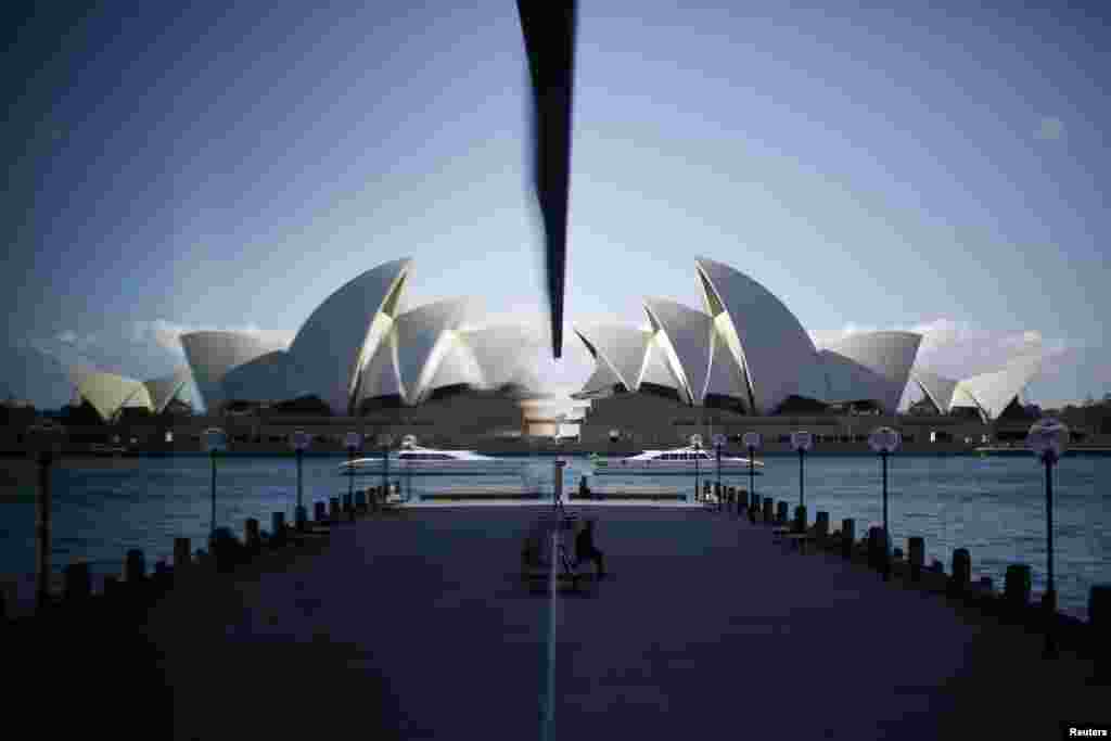 The Sydney Opera House is reflected in a harborside hotel window in The Rocks district of Sydney, Australia.