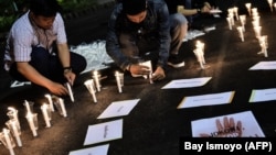 Sejumlah pengunjuk rasa menyalakan lilin dalam demo di depan istana kepresidenan untuk memprotes hukuman mati, Jakarta, 28 Juli 2016. (Foto: Bay Ismoyo/AFP) 