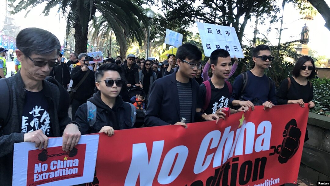 FILE - Protesters hold a banner as they walk down Elizabeth Street in Sydney during a protest against Hong Kong's proposed extradition law, June 9, 2019.