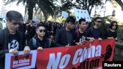 FILE - Protesters hold a banner as they walk down Elizabeth Street in Sydney during a protest against Hong Kong's proposed extradition law, June 9, 2019.