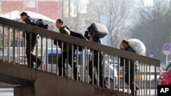 Migrant workers carrying their belongings walk up an overpass near the railway station upon arriving in Beijing, 02 March 2010