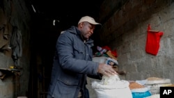 Penjual beras Francis Ndege tampak mengukur beras di kiosnya di Pasar Toi, Nairobi, Kenya, pada 9 Agustus 2023. (Foto: AP/Brian Inganga)