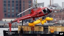 Un hélicoptère est hissé par une grue de l'East River sur une péniche, le 12 mars 2018, à New York. 