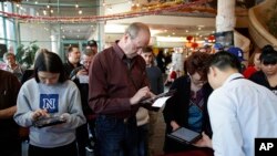 People sign in on tablet computers at an early voting location in the Chinatown Plaza, Feb. 15, 2020, in Las Vegas.