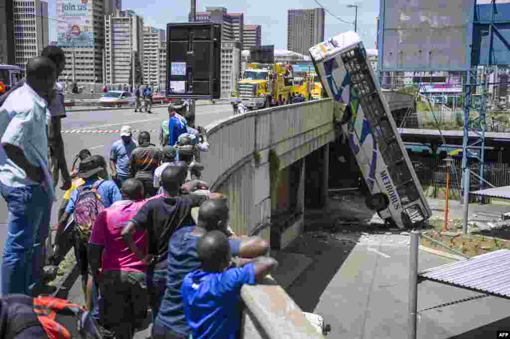 Onlookers gather on Queen Elizabeth bridge to look at a public transport bus that drove over the side of the bridge in Johannesburg, South Africa. No fatal injuries were reported and the bus driver had minor injuries.