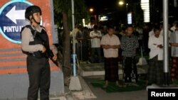 Polisi menjaga warga Muslim yang sedang salat di hari pertama Ramadan, dekat Markas Polda Bali di Denpasar, Bali, 16 Mei 2018.